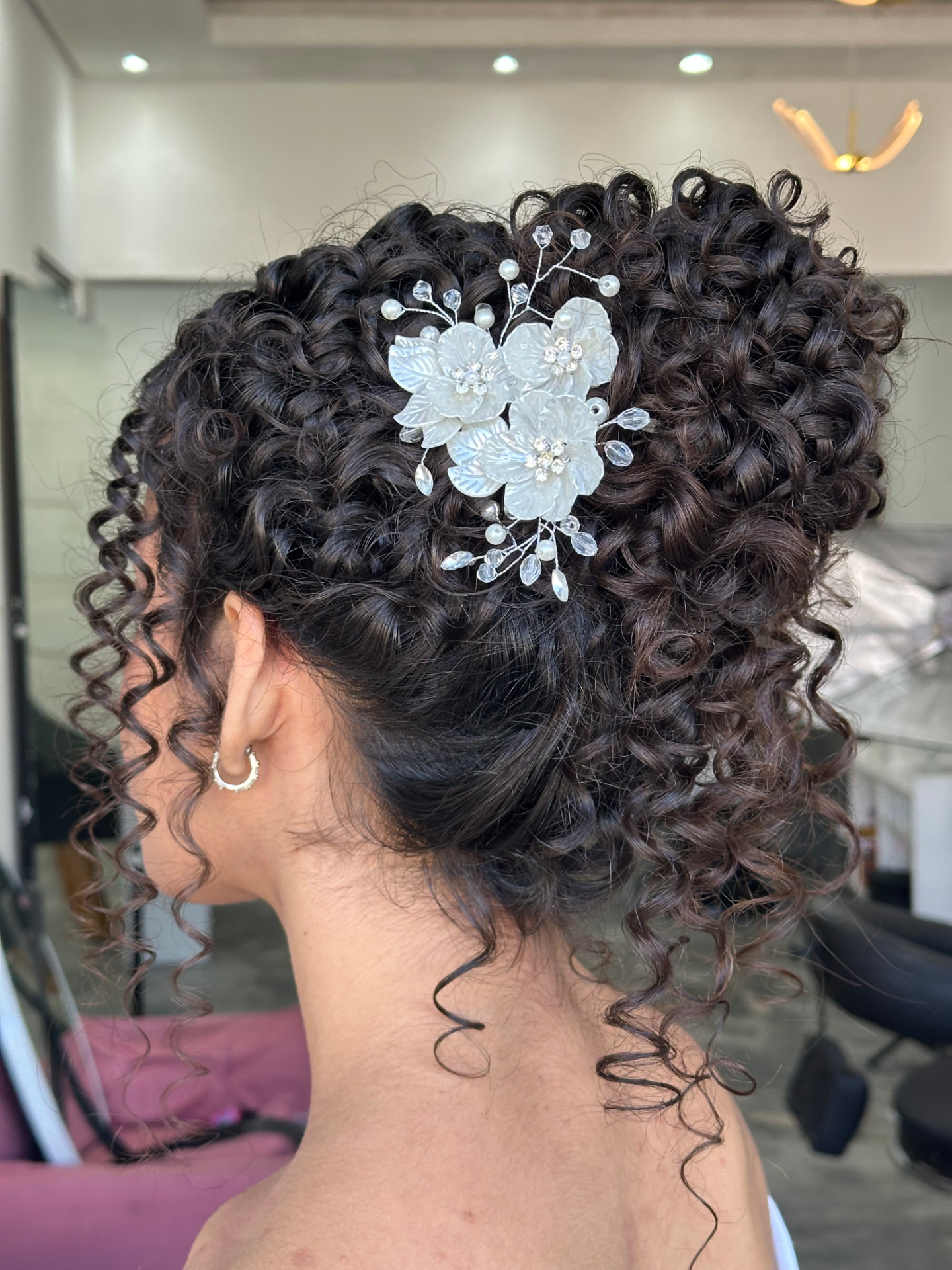 Penteado em cabelo cacheado com acessório de flores